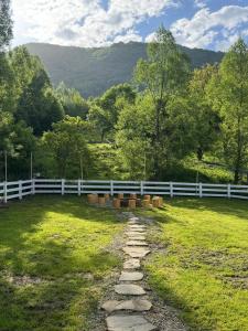 a stone path in a field next to a white fence at Cabana Gala Doftanei in Trăisteni
