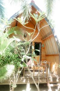 a wooden cabin with a porch and some palm trees at Banana Leaf Bungalow in Gili Trawangan