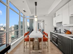 a kitchen with a white table with orange chairs at VOGUE Suites Toronto in Toronto
