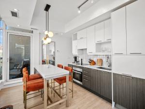 a kitchen with white cabinets and a table and chairs at VOGUE Suites Toronto in Toronto