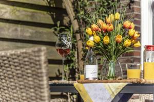 a table with a glass of wine and a vase of flowers at Ferienhaus Lillys Beachhouse in Varel