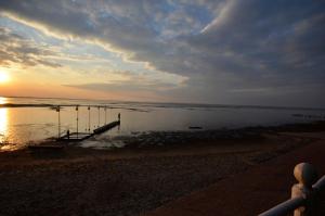 a beach with a dock in the water at sunset at Ferienhaus Lillys Beachhouse in Varel +20 photos