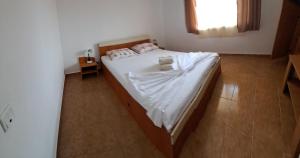 a bedroom with a bed with white sheets and a window at Vila Coralia in Schitul +5 photos