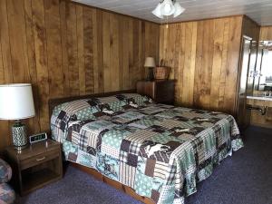 a bedroom with a bed and a table with a lamp at Bambi Motel in East Tawas +1 photo