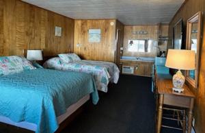 a bedroom with two beds and a desk with a lamp at Bambi Motel in East Tawas