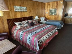 two beds in a room with wood paneled walls at Bambi Motel in East Tawas