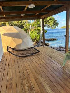 an umbrella sitting on a wooden deck next to the ocean at Dôme en face de la Passe de Tiputa in Rangiroa