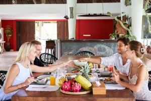 a group of people sitting around a table eating food at Ayurvedagram Bali - Wellness & Retreat Resort in Ubud