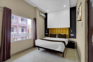 a bedroom with a bed and a large window at Super Hotel O Kashi Ghat Varanasi Formerly Ganga Valley in Rāmnagar