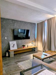 a living room with a couch and a tv on a wall at Apartments 18 - Central & Cozy in Velingrad