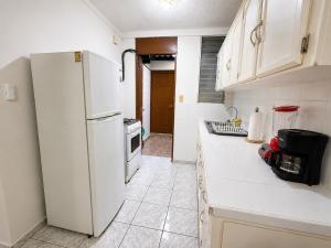 a kitchen with a white refrigerator and white cabinets at Gosen Stays in Antiguo Cuscatlán
