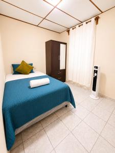 a bedroom with a bed with a blue blanket at Gosen Stays in Antiguo Cuscatlán