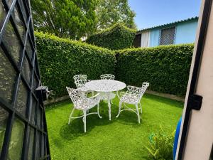 a patio with a table and chairs on the grass at Gosen Stays in Antiguo Cuscatlán