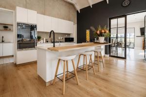 a kitchen with white cabinets and a island with bar stools at Moorlands Manor in George