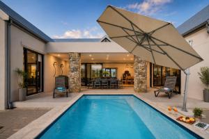 a swimming pool with an umbrella next to a house at Moorlands Manor in George