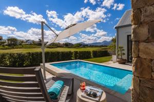 a swimming pool with an umbrella next to a chair and a table with an umbrella at Moorlands Manor in George