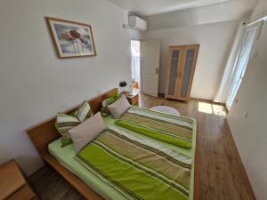 a bedroom with a large bed with green sheets at Fenyves Ferienhaus 2 **** in Balatonfenyves