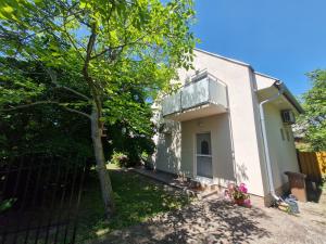 a white house with a tree and a fence at Fenyves Ferienhaus 2 **** in Balatonfenyves +4 photos