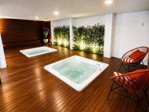 a living room with a hot tub and two chairs at Pousada Safari in Penha