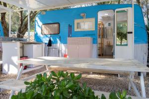 a picnic table in front of a blue trailer at Camping Car Palmasera in Cala Gonone
