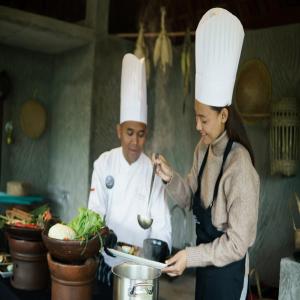 a man and woman in chefs hats preparing food in a kitchen at Plataran Bromo in Bromo +158 photos