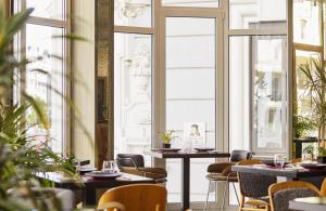 a restaurant with tables and chairs and windows at Hyatt Centric Gran Via Madrid in Madrid