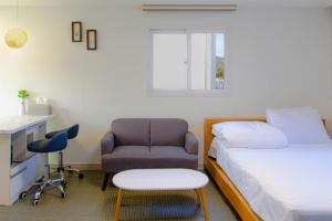 a bedroom with a bed and a chair and a desk at Beachblue Pension Geoje in Geoje