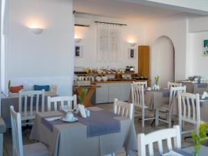 a dining room with tables and chairs and a kitchen at Rhenia Mykonos Hotel & Bungalows in Tourlos +57 photos