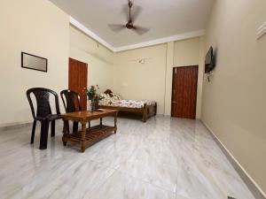 a living room with a table and chairs and a bed at Serinity Saral in Pondicherry