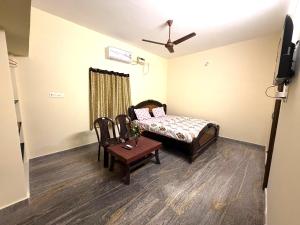 a bedroom with a bed and a table and a tv at Serinity Saral in Pondicherry