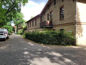 a brick building with a balcony on the side of a street at Logierhaus Hoppegarten direkt an der Rennbahn mit perfekter S-Bahn Anbindung in Hoppegarten