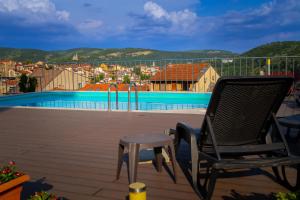 a chair sitting on a deck next to a swimming pool at Hide Hub Guest Apart in Veliko Tŭrnovo