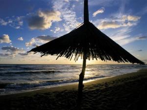 a straw umbrella on a beach with the ocean at Vanilla House in Ulcinj