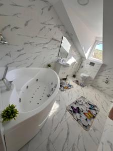 a white bathroom with a large tub and marble floor at Casa Happy in Petroşani +22 photos