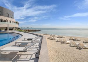 a resort with a pool and chairs and the beach at Ray Hotel by Cloud 7 in Kuwait