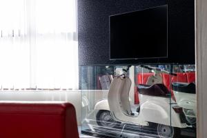 a scooter in a glass case with a tv on top at Hotel Cavallino in Faenza