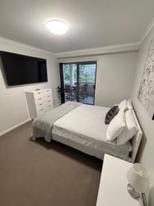 a bedroom with a bed and a television and a table at Jubilee Apartment 08 - Bring your own linen in South West Rocks +12 photos