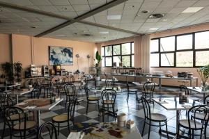a dining room with tables and chairs and windows at Hotel Cavallino in Faenza