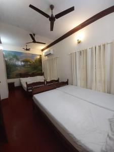 a bedroom with two beds and a ceiling fan at Taj Mahal Hotel in Cochin +58 photos