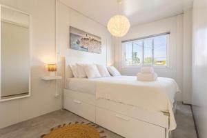 a white bedroom with a large bed and a window at Casa das Flores by Hostiva in Aroeira