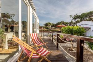 a deck with chairs and an umbrella on a house at Casa das Flores by Hostiva in Aroeira