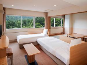 a hotel room with two beds and a desk at AZUMINO KOGEN Resort in Azumino +112 photos