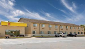 a large building with a car parked in a parking lot at Super 8 by Wyndham Macomb in Macomb