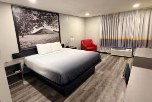 a hotel room with a bed and a red chair at Super 8 by Wyndham Macomb in Macomb