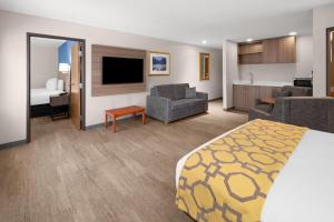 a hotel room with a bed and a living room at Baymont by Wyndham Salida in Salida