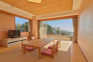 a dining room with a table and chairs and a large window at Pleasure Resort Izu Akazawa Onsen in Ito