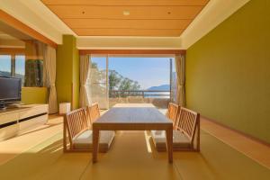 a dining room with a table and chairs and a large window at Pleasure Resort Izu Akazawa Onsen in Ito