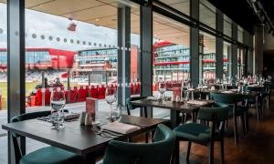 a restaurant with tables and chairs with wine glasses at Hilton Garden Inn Manchester Emirates Old Trafford in Manchester