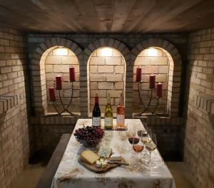 a table with wine bottles and a bowl of grapes at Dura Guesthouse, Garden Wellness Retreat near the Tisza River in Paszab