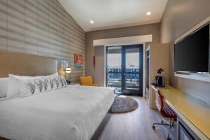 a bedroom with a large bed and a flat screen tv at Bluestem Hotel Torrance Los Angeles, an Ascend Collection Hotel in Torrance